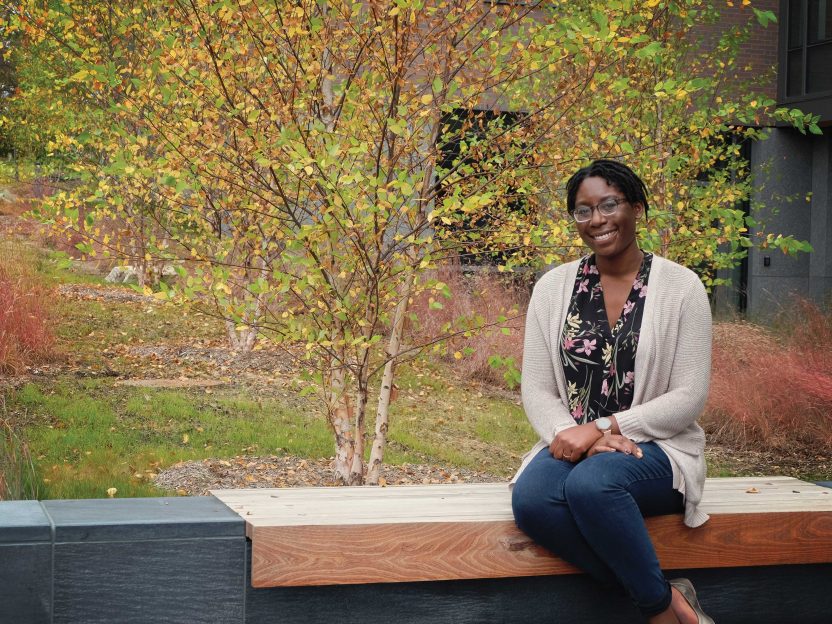 Portrait of Shivon Robinson sitting outside on a wooden bench