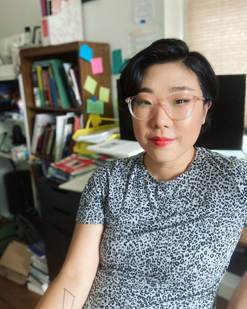 frannychoi headshot copy Portrait of Franny Choi sitting in an office with a cluttered desk behind her