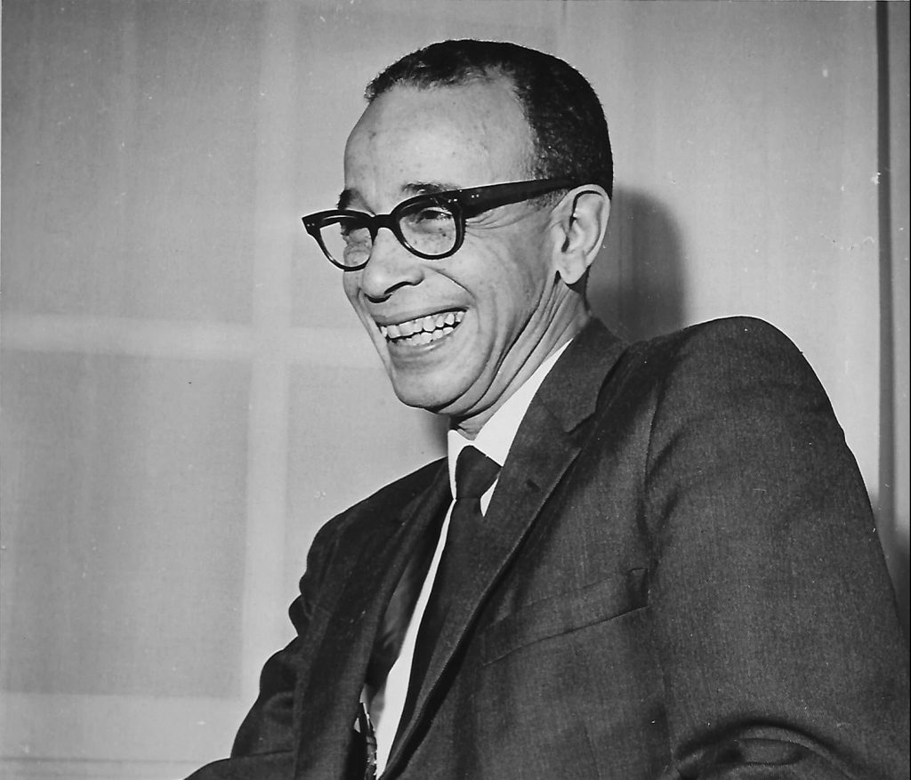 Lloyd12 Photo of Rupert Lloyd smiling and holding a pipe.
