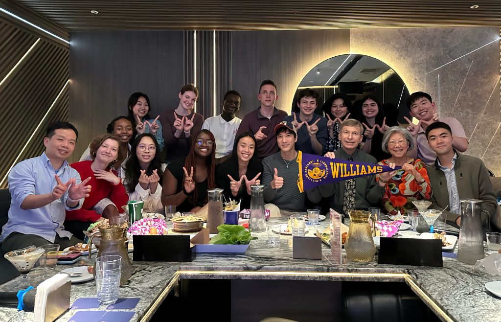 Students gathered around a table at a restaurant with singer Leehom Wang '98