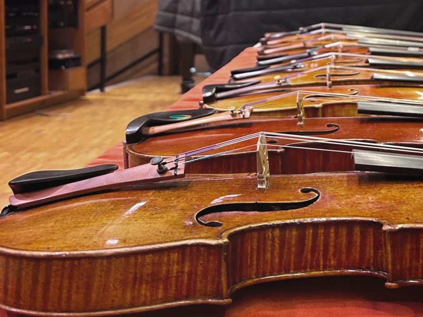 About a half-dozen violins rest side by side on a table in the Brooks Rogers auditorium.
