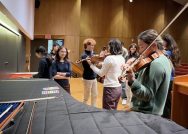 A few students trying out a violin in a theater space