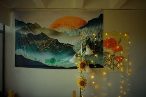 The wall of a college dorm room is decorated with a flag and lights.