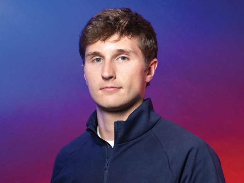 A full page headshot style photo of Ben Washburn against a wash of blue and purple.