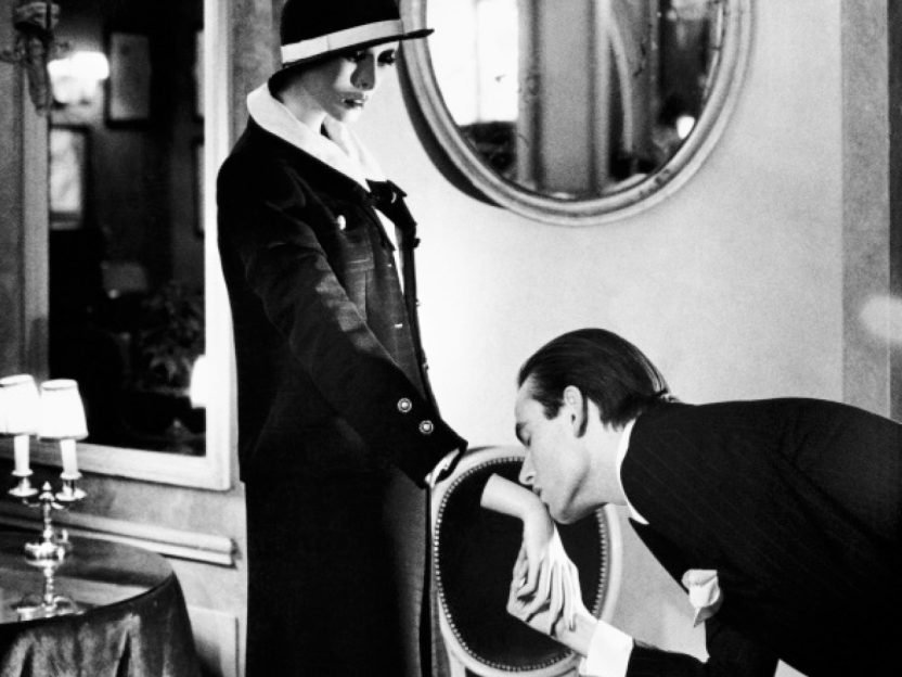 A black and white photo of a man kissing the hand of a mannequin