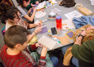 Students and other participants gather at a table to work on a craft project during Claiming Williams Day