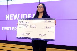 A person holds a giant check from Williams for first place, $2,000.