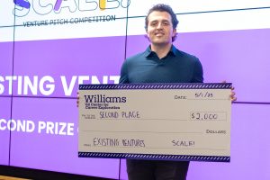A person holds a giant check from Williams for second place, $2,000.